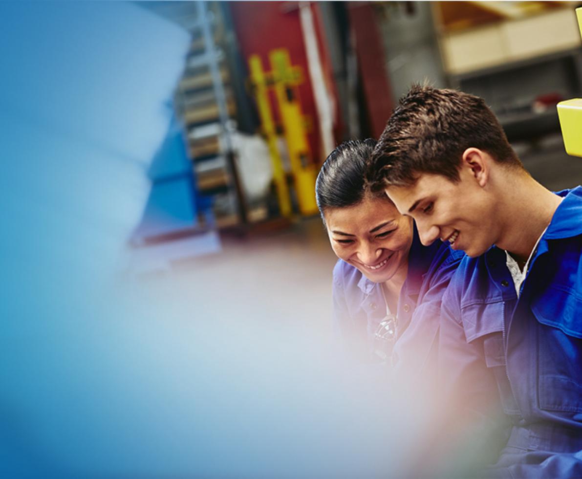 A woman and man having a conversation on a production site/warehouse.