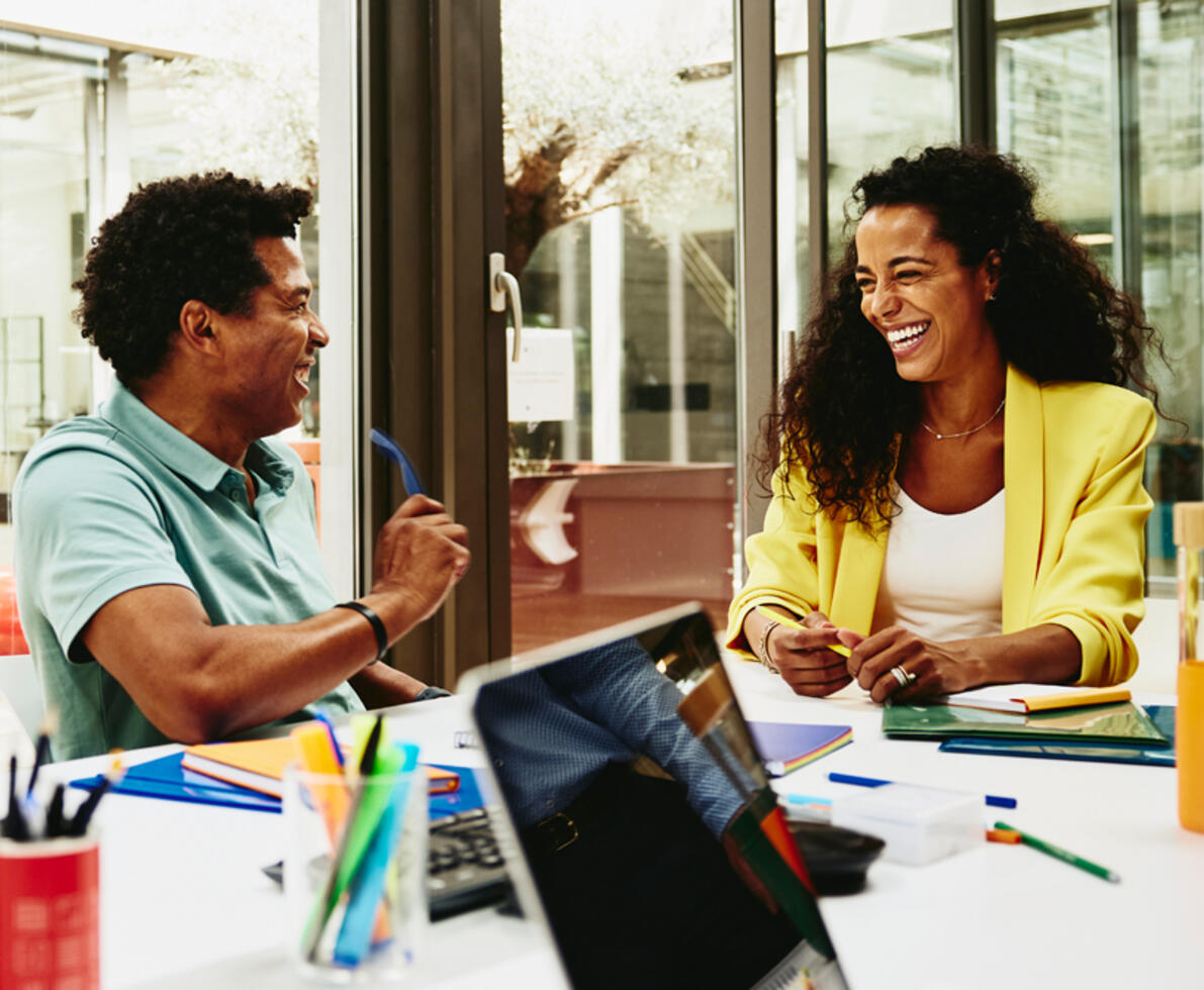 Man and woman having a laugh during a meeting in a meeting room.