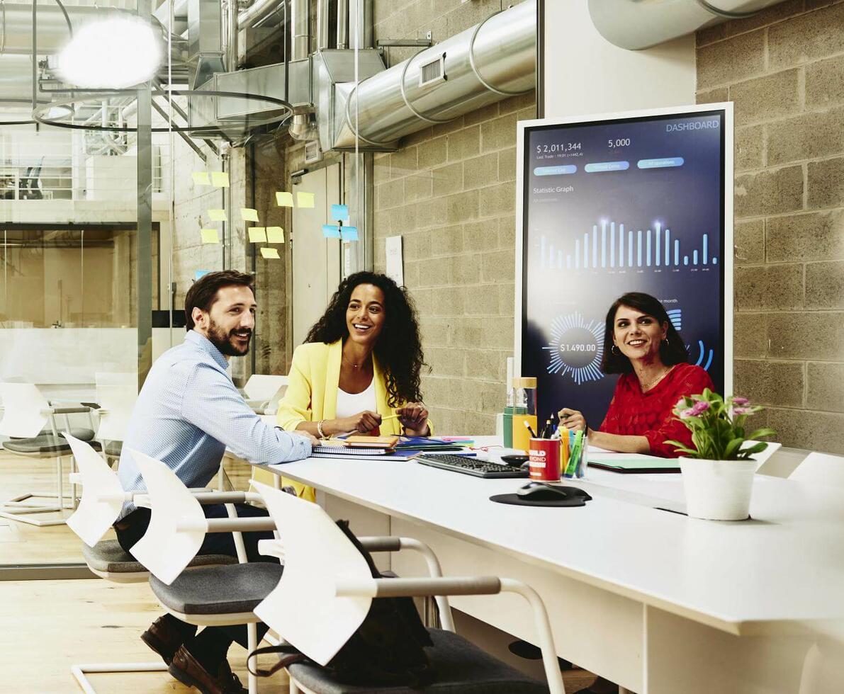 Three colleagues having a meeting in a meeting room, while one colleague is making a call outside the room.