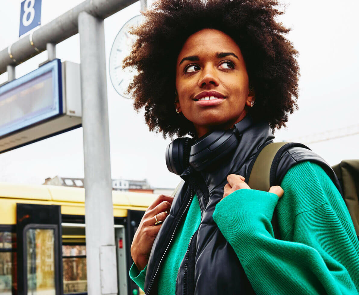 Smiling woman, looking away on train platform. Train in background.