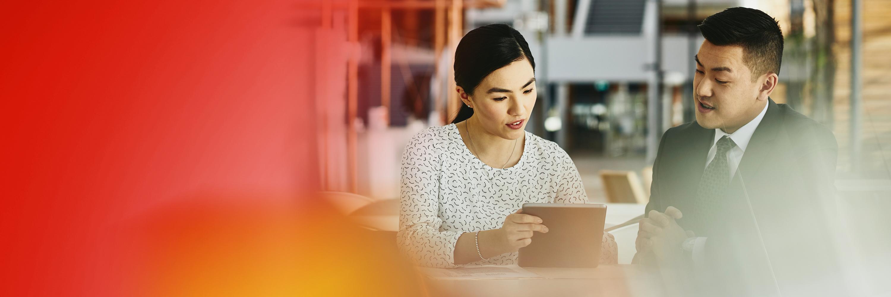 Man and woman working together on a tablet. Both looking down.