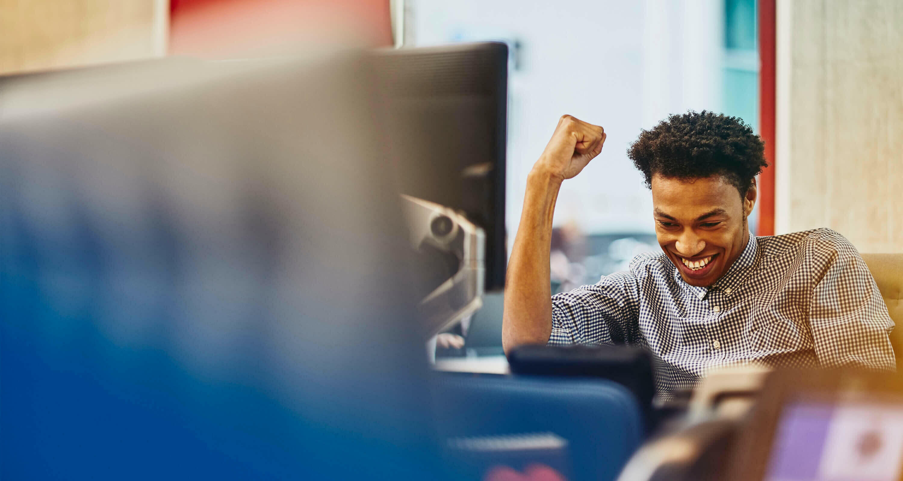 Man sitting at a desk in an office smiling looking happy.