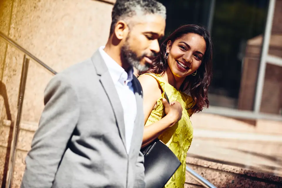 male and smiling female walking outside in the sun.